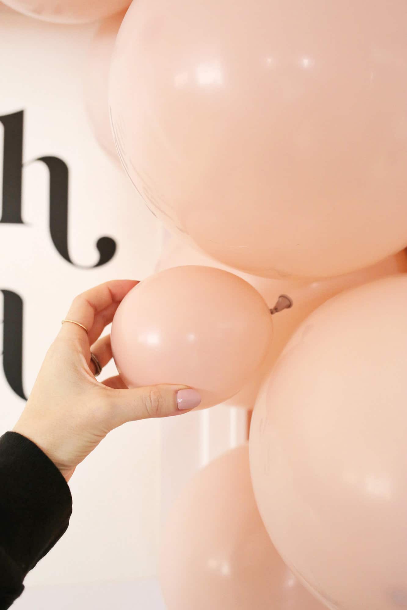 adding pink balloons to garland over table