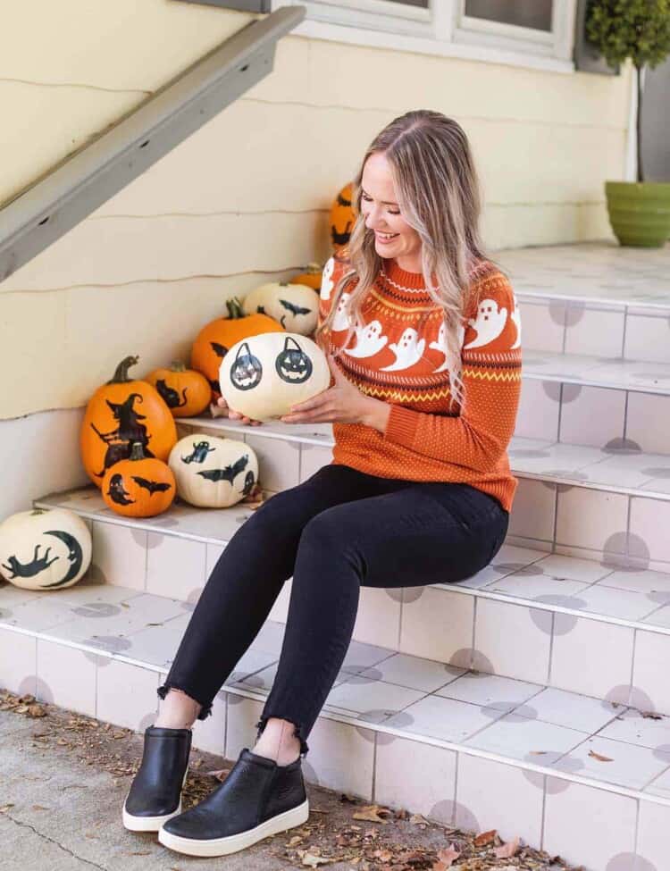 woman holding white pumpkin on porch
